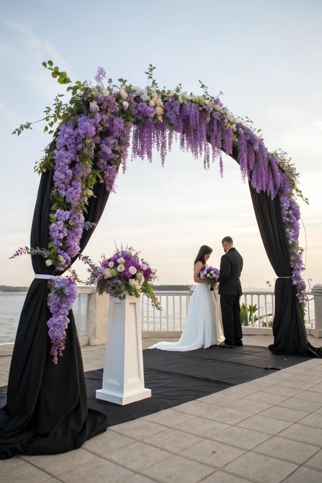 An enchanting ceremony arch with purple wisteria and black drapery.