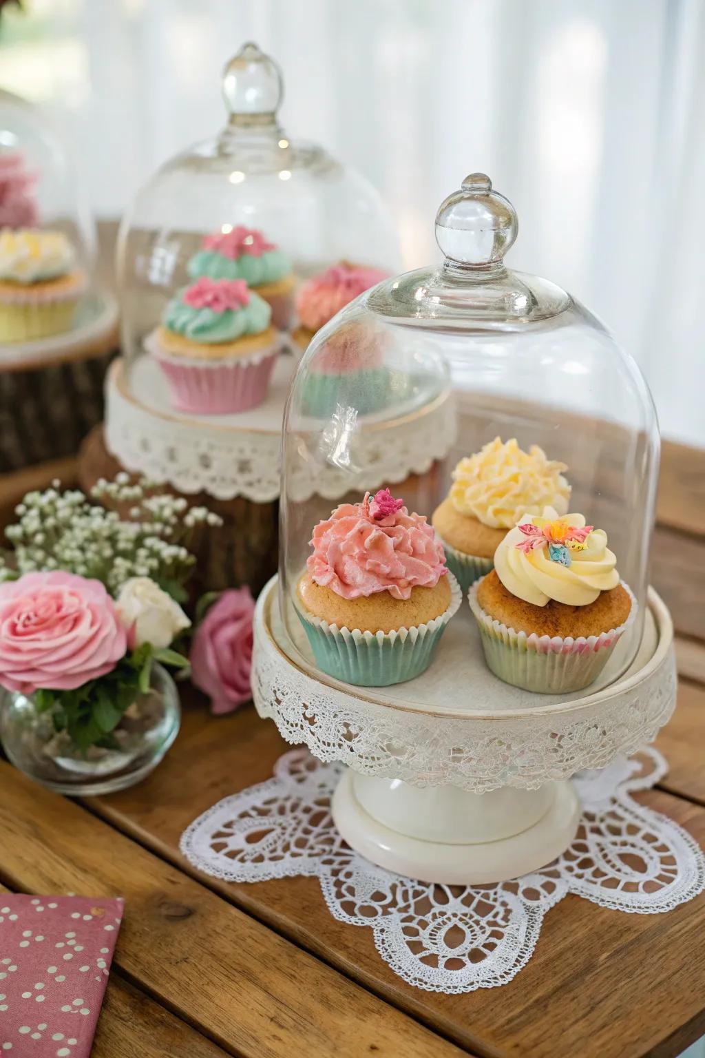 Glass cloches add sophistication and an elegant touch to the cupcake display.