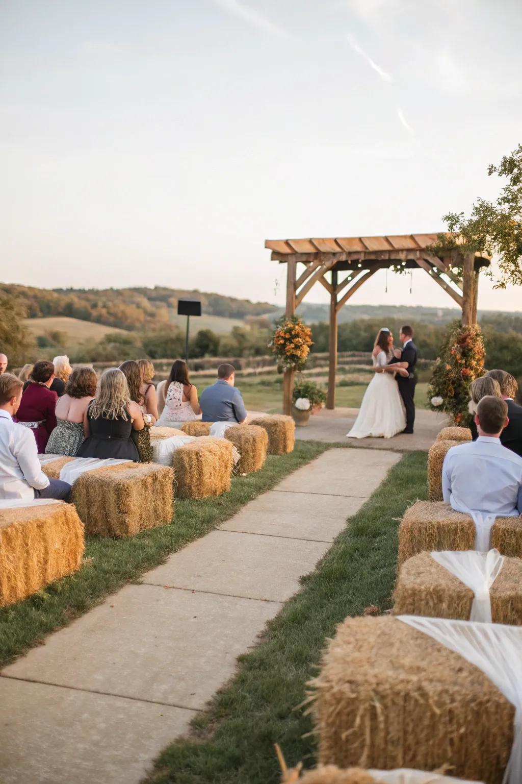 A rustic wedding ceremony with hay bale seating covered in comfortable fabric.